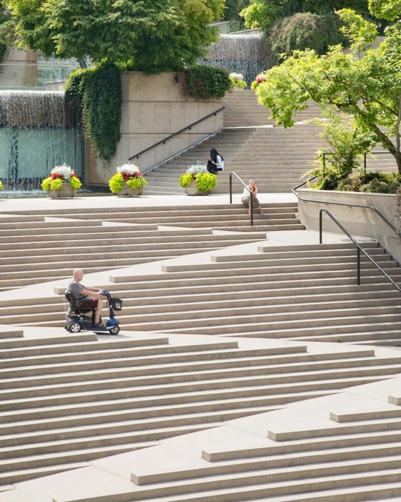 Design inclusivo e accessibilità: le stramp come esempio negativo di progettazione. Nella foto un esempio di stramp: scale combinate con rampe. Le sta percorrendo una persona in sedia a rotelle.