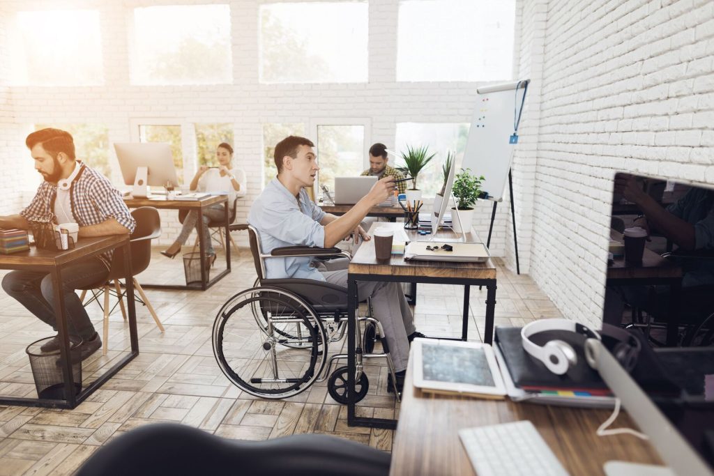Design inclusivo e accessibilità: nell'immagine uno studio accessibile in cui sono presenti tre persone, di cui una in sedia a rotelle.