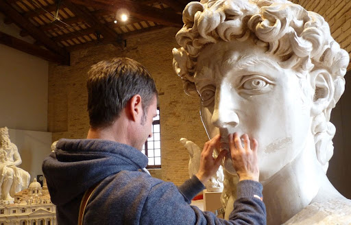 Musei tattili in Italia: un uomo tocca la riproduzione del David di Michelangelo al Museo Tattile Statale Omero